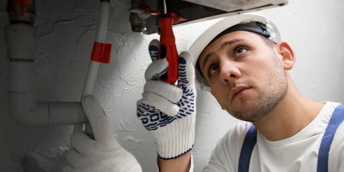 Plumber doing work under a sink in a commercial building, representing the work plumbers do in New Bedford, MA
