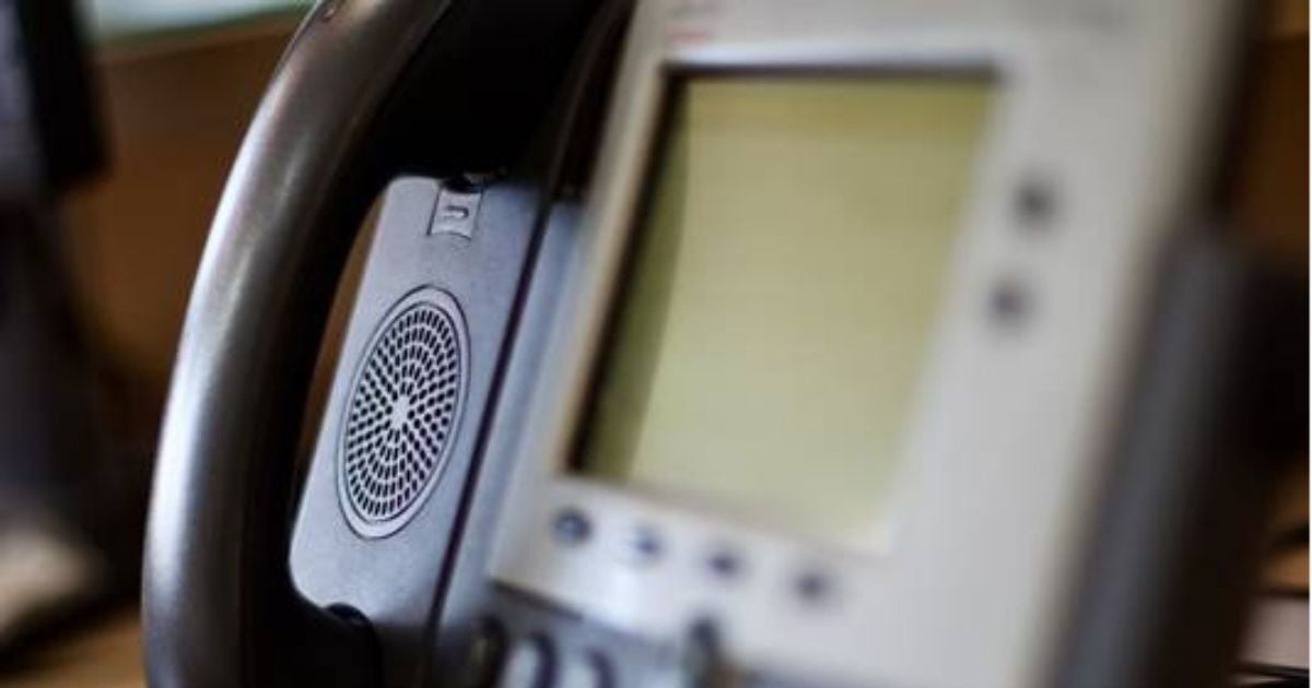 PhoneClose-up of an office desk phone with a corded handset and digital display screen, commonly used for business communication.