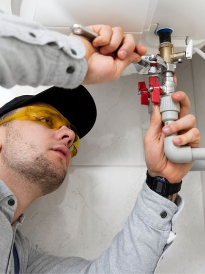 Plumber working under sink