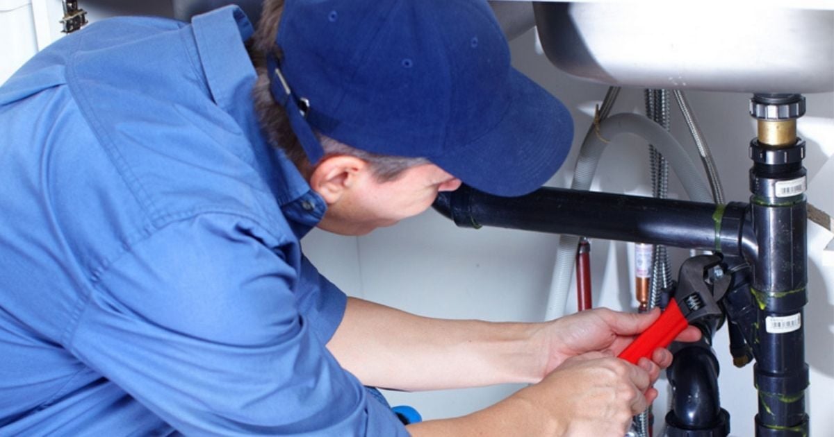 Plumber working under sink