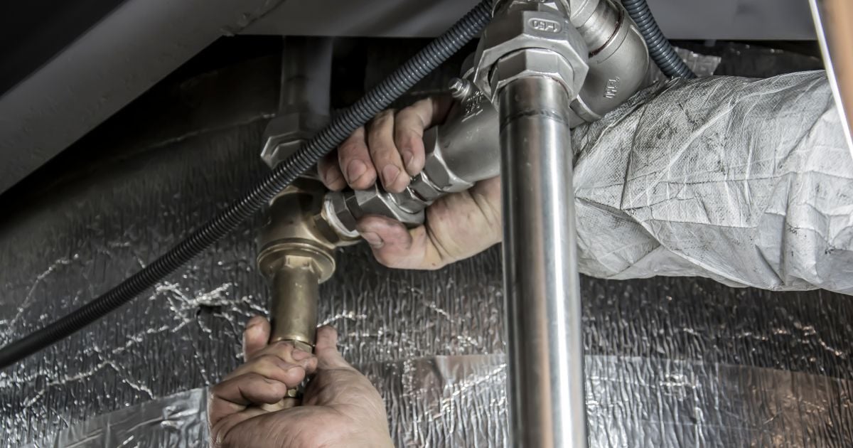 Hands working on a pipe in a tight space