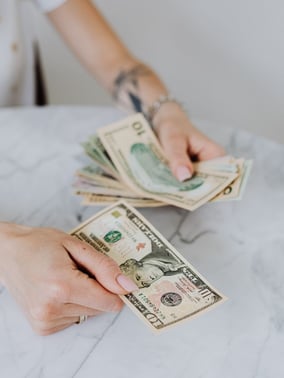 Person counting money representing the cost and payment for commercial HVAC services in Somerville, MA