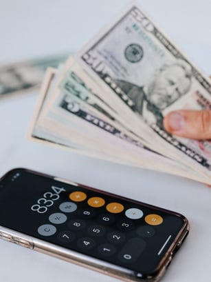 Money and a calculator representing saving money with regular commercial plumbing maintenance