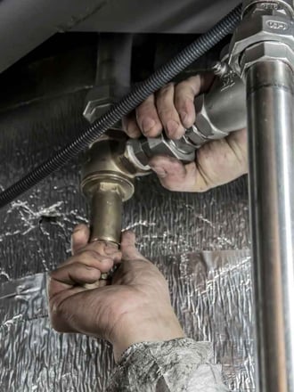 Plumber fixing a broken commercial plumbing pipe