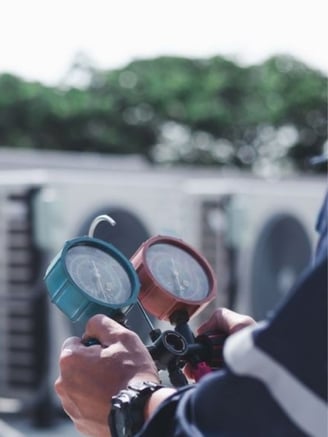 HVAC technician checking multiple HVAC units with measuring equiptment during a maitenance call