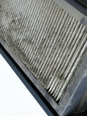 Dirty HVAC air filter visibly clogged with debris, illustrating how restricted airflow can affect building performance and indoor air quality.