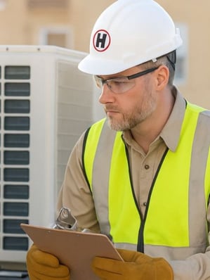 HVAC service tech checking a commercial unit while on a preventative maintenance call