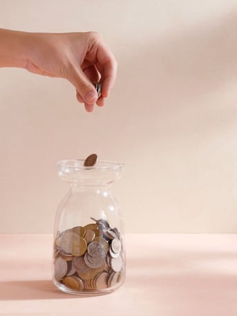 Dropping change into a jar representing the savings by lowering operating costs with maintenance