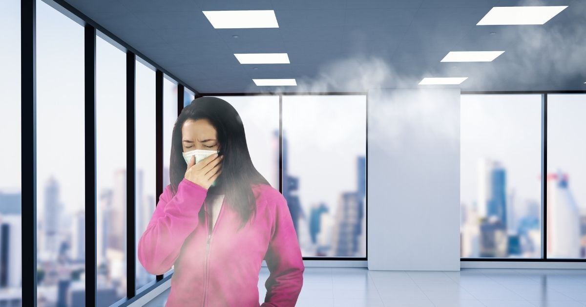 Woman in office with bad air quality leading to health issues and discomfort. 